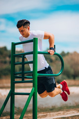 Wall Mural - Fitness man doing dips at outdoor gym workout