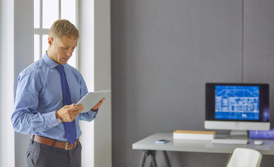 Portrait of smiling happy young entrepreneur standing at his of