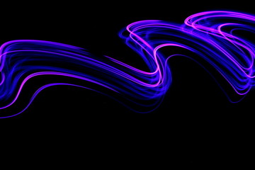Wall Mural - Long exposure photograph of neon pink and purple colour in an abstract swirl, parallel lines pattern against a black background. Light painting photography.