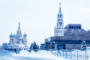 Wall Mural - Moscow Red Square in winter, Russia. This place is a famous tourist attraction of Moscow. Cold winter view of St Basil Cathedral and Moscow Kremlin. Panorama of Moscow city center during snowfall.