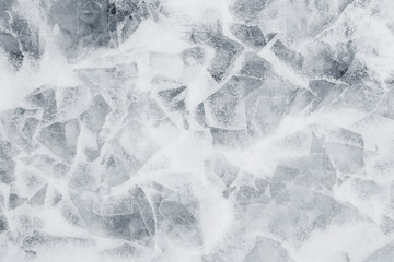 Close-up of snow on cracked and thin layers of ice in the winter. Simple and minimal full frame abstract background in black and white. Copy space.