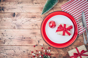 Wall Mural - Christmas table setting with plate, gift box and  decorations on wooden background.