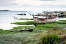 The Noirmoutier Boats Cemetery. The Wreck Of An Old Fishing Boat Is Stranded On The Vegetation That Grows On The Edge Of The Mudflat