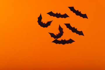 Halloween and decoration concept. Black paper bats flying over orange background.