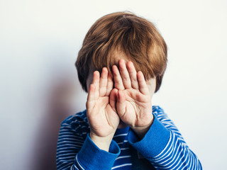 sad little boy covered his face with his hands, child psychology and emotions