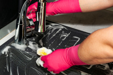 Wall Mural - The process of washing the dark sink, hands close-up. A man in pink gloves washes a sink. Cleaning, clean up.