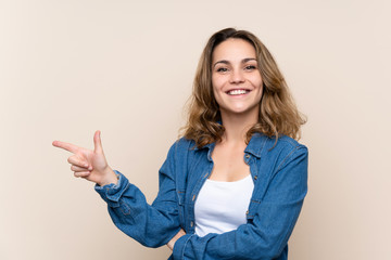 Wall Mural - Young blonde woman over isolated background pointing finger to the side