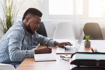 Poster - Employee using laptop and taking notes while working in office