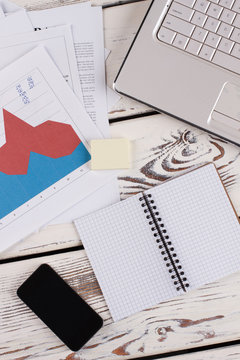Papers with graphics, stationery and devices. Office tabletop close up.