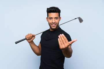 Poster - Handsome young man playing golf over isolated blue background inviting to come with hand. Happy that you came