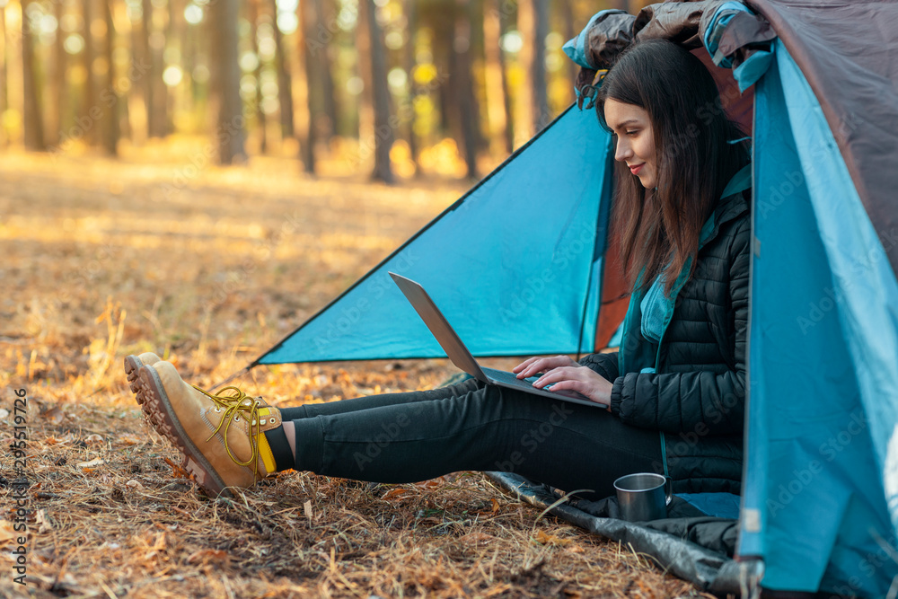 Young girl using laptop in camping tent - obrazy, fototapety, plakaty 