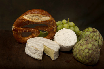 Brie cheese, cheese empanada, beige, bunch of green grapes and two custard apples