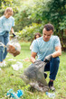 © Viktoriia - Volunteering. Young people volunteers outdoors africa boy close-up picking litter into plastic bag concentrated