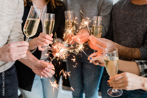 Fotografía Group of friends holding flutes of sparkling champagne and burning bengal lights