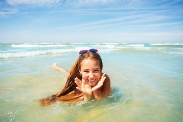 Wall Mural - Cute girl play in waves holding palms near face