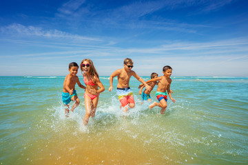 Sticker - Group of children run from the ocean holding hands