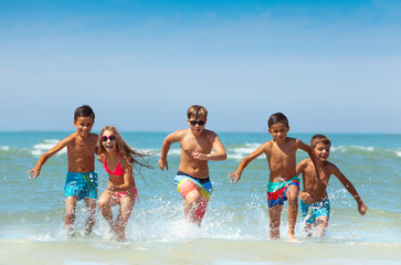 Canvas Print - Group of kids running from the sea with splashes