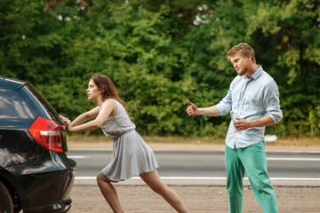 Wall Mural - Young couple pushing broken car on road, breakdown