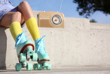 Young woman with vintage roller skates and radio sitting on stone stairs, closeup view