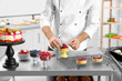 Male pastry chef preparing dessert at table in kitchen, closeup