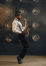 Black Jazzman In Hat Plays The Saxophone On Stage