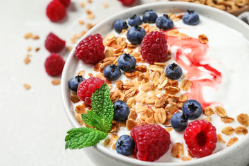 Tasty homemade granola with yogurt and berries on light table, closeup. Healthy breakfast