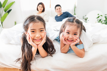 Happy Asian family laying on bed in bedroom with happy and smile