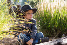 6 Year Old Boy Wearing Hat Outdoors In Field Of Tall Grass