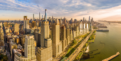 Fototapete - Aerial panorama of New York City waterfront skyline at sunset viewed from above River Side Park, along Joe DiMaggio highway and Riverside Blvd, next to Hudson River.