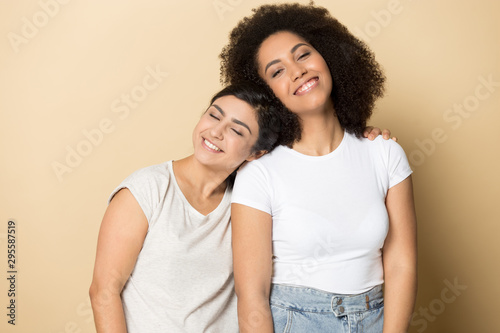 Fotografía Smiling multiethnic girlfriends hug isolated in studio