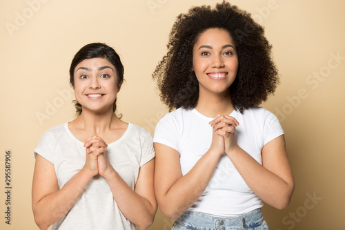Cuadros en Lienzo Smiling international girlfriends with hands in prayer hope for best