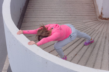 Young female runner in prepairing for jogging in the city street.Fit body requires hard work. Urban sport concept. Young female exercising in sport clothes.