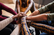 © JonoErasmus - Cropped close of diverse businesspeople putting their hands on top of each other wearing casual clothes and african patterns.