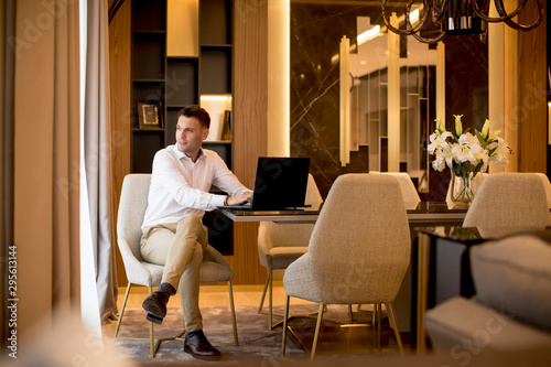 Business man sitting in a luxurious room in front of a laptop Tableau sur Toile