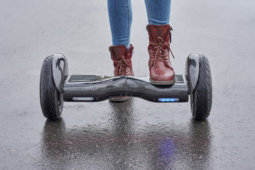 Close up of woman using hoverboard on asphalt road. Feet on electrical scooter outdoor