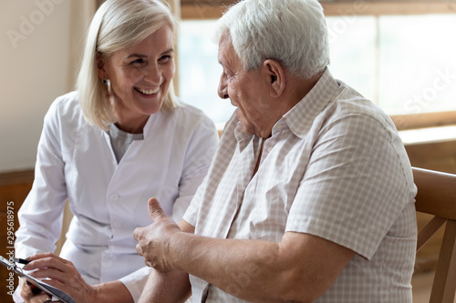 Cuadros en Lienzo Elderly man patient and middle-aged nurse talking indoors
