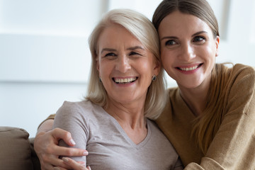 Wall Mural - close up photo adult daughter cuddles old mother