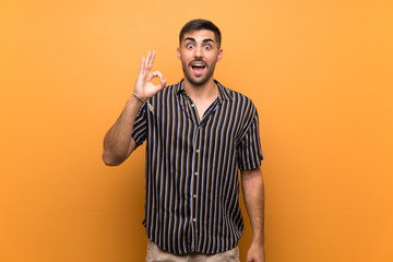 Handsome man with beard over isolated background surprised and showing ok sign