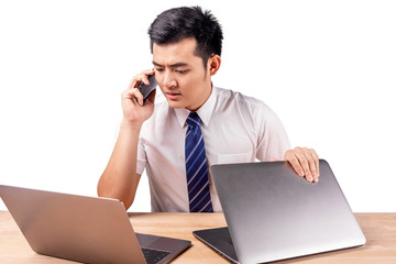 serious asian businessman talking on cellphone with 2 laptop