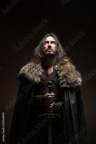 Fotomural Man dressed in medieval armor and raincoat with longs word fighting against enemy