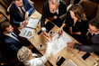 © alfa27 - Young formal dressed business woman shaking hand with old mirthful partner sitting at conference dest, top view