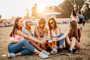 Wall Mural - Female friends cheering with beer at music festival