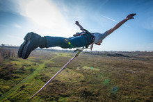 Man Bungee Jumping On Green Meadow Background