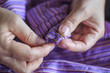© Jedsada Naeprai - Hand of the seamstress is using a needle to sew purple cloth hook by hand close-up.