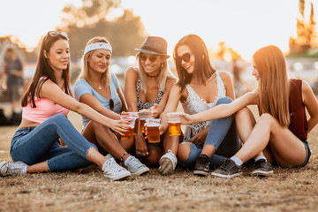 Wall Mural - Female friends cheering with beer at music festival