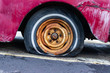 A flat tire on a red antique pickup truck.