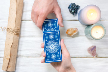 Wall Mural - Tarot cards in fortune teller hand on white wooden table background. Future reading.