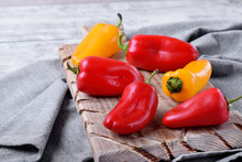 Little Red And Yellow Bell Peppers On Wooden Board