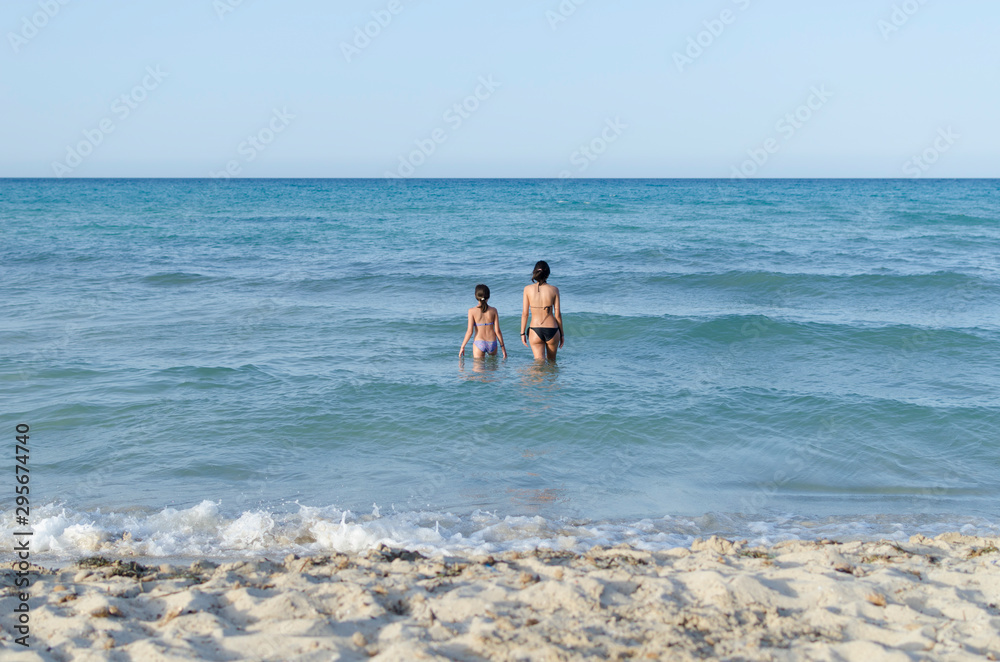 Foto de Stock NIÑAS EN PLAYA MURO BAÑANDOSE | Adobe Stock