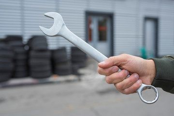 Hand auto mechanic and wrench on the background of the garage. Auto repair concept.